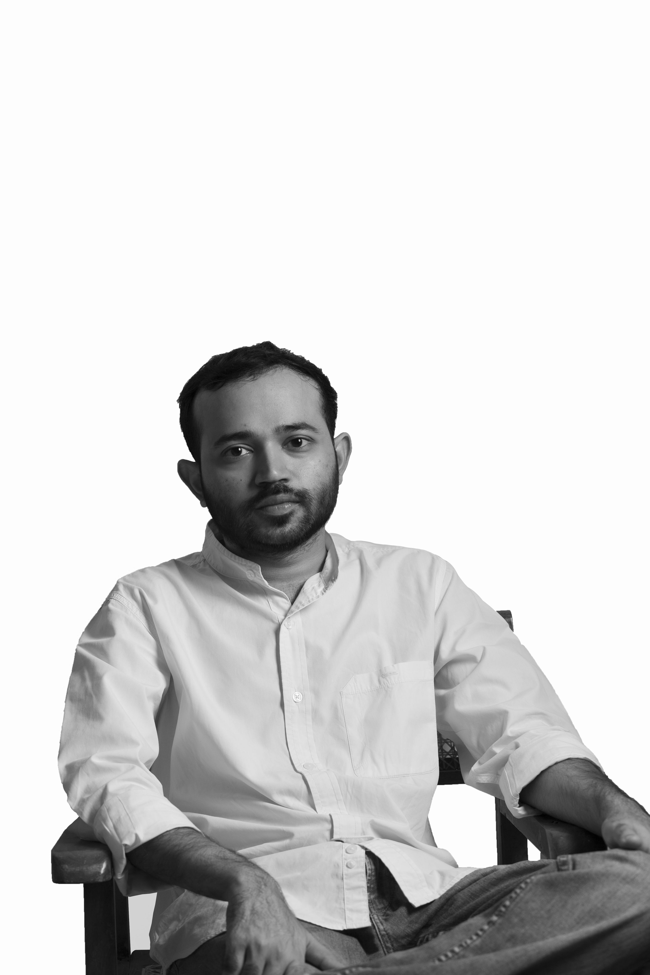 Black and white photo of a person sitting in a chair, wearing a white shirt and jeans.